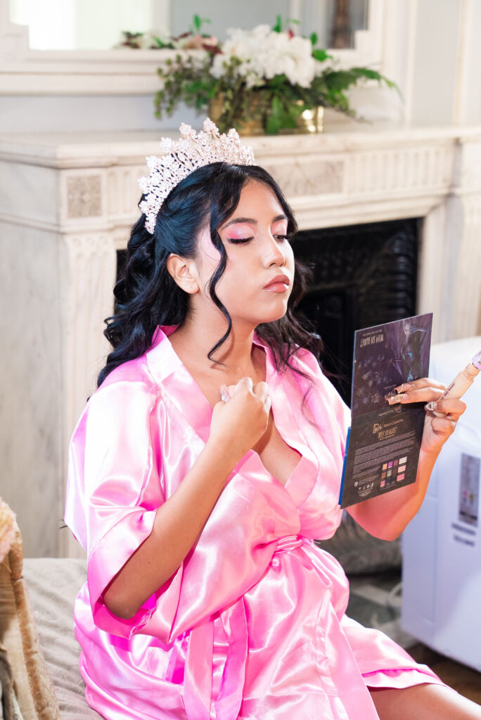 Quinceañera getting ready in a pink robe, captured by our event photographer