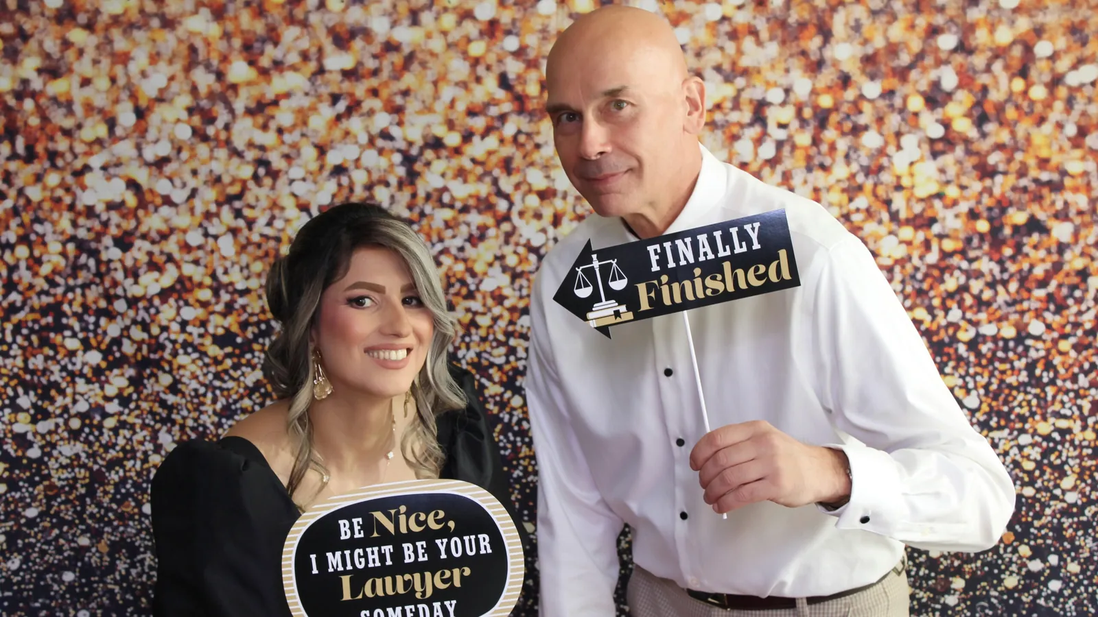 Couple with props in front of a gold sequin backdrop at a Signature Classic photo booth in Toronto